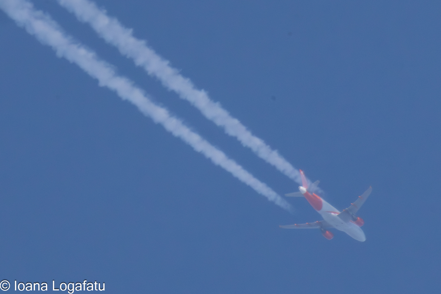 Contrails stretch across a clear blue sky above